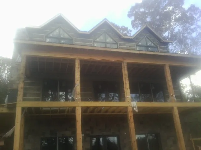 Dormers and porch framing on a large log home under construction — Roof Coating work by our crew in La Junta