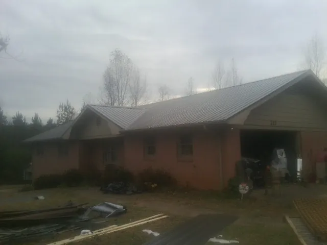 Gray metal roof on a stucco house with an attached garage in La Junta