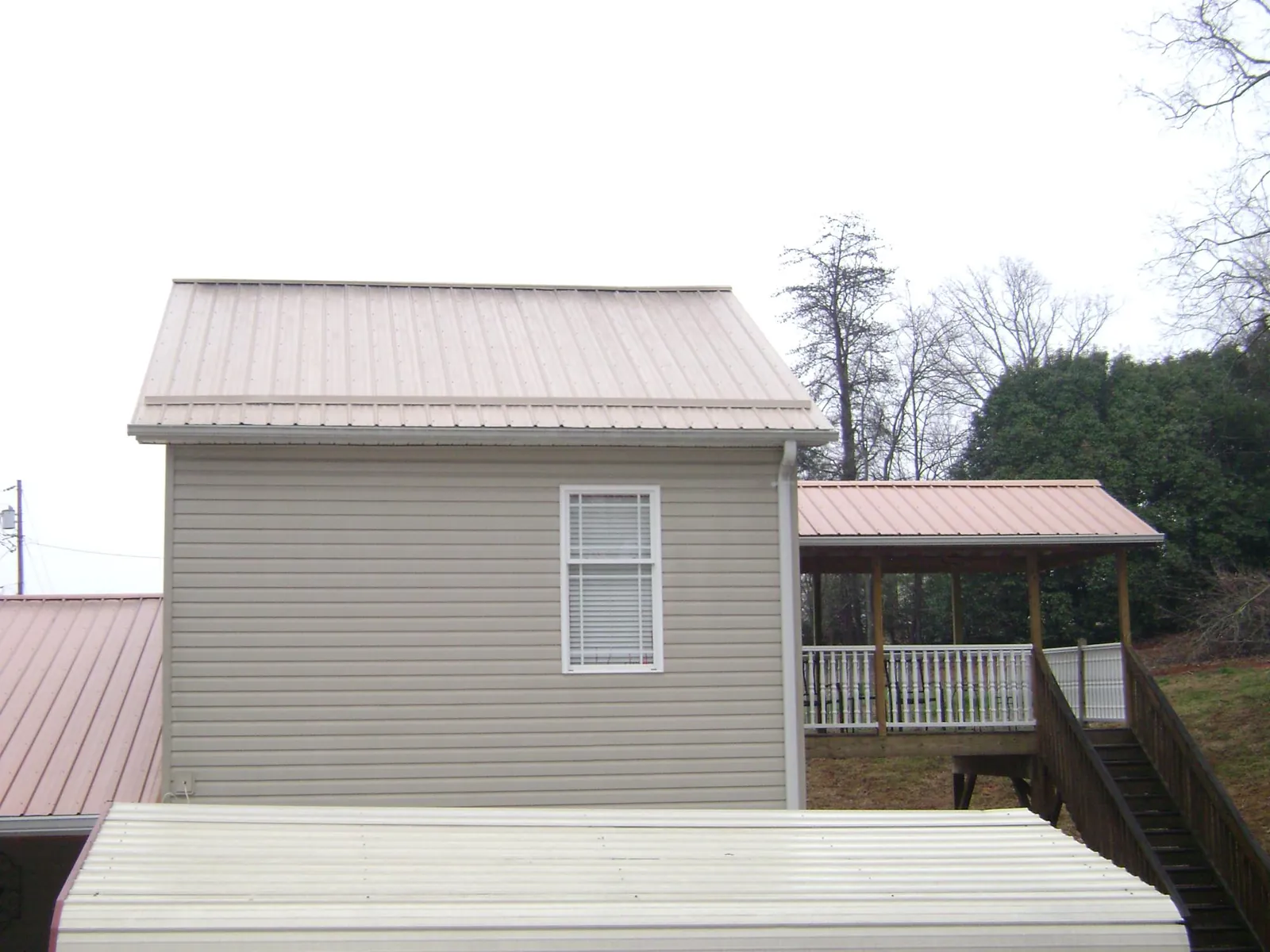 Tan metal roofs on a two story addition and attached porch, from a Roof Replacement job in La Junta